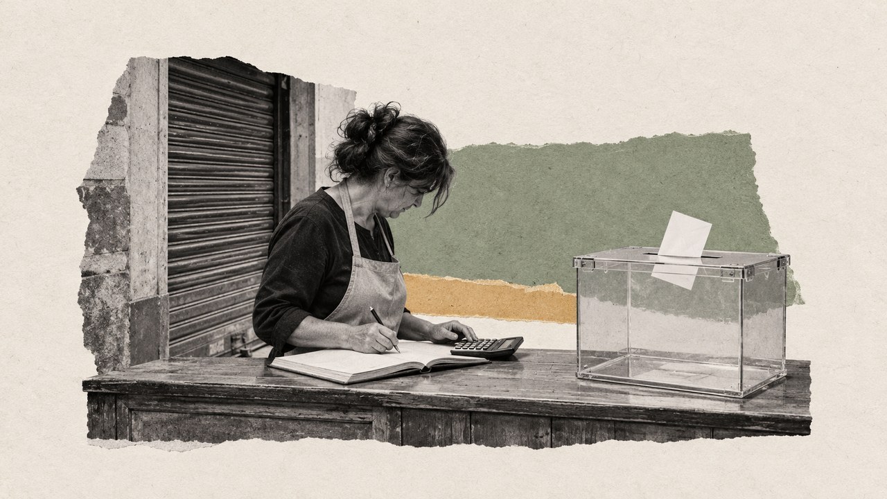 Una mujer con delantal hace cuentas con una calculadora y un libro junto a una urna, ante una persiana de comercio.